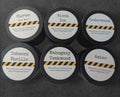 Six candle jars with different scents on each label, on a stone background