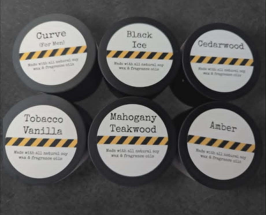 Six candle jars with different scents on each label, on a stone background
