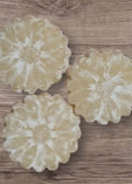 Three round, white floral-patterned cookies on a wooden surface