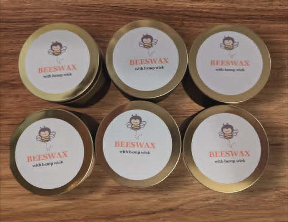 Beeswax candles in tins on a wooden surface