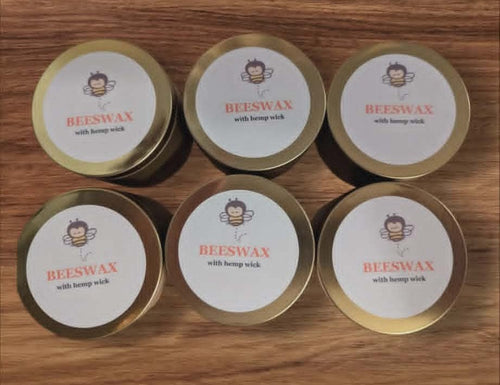 Beeswax candles in tins on a wooden surface