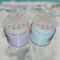 Two jars of bath salts, one peppermint and one lavender, on a stone surface