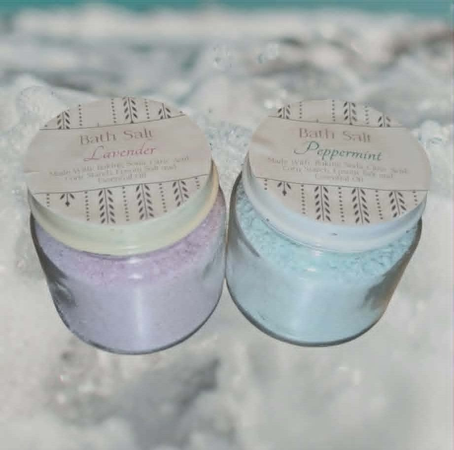 Two jars of bath salts, one peppermint and one lavender, on a stone surface