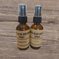 Two brown spray bottles with labels on a wooden surface