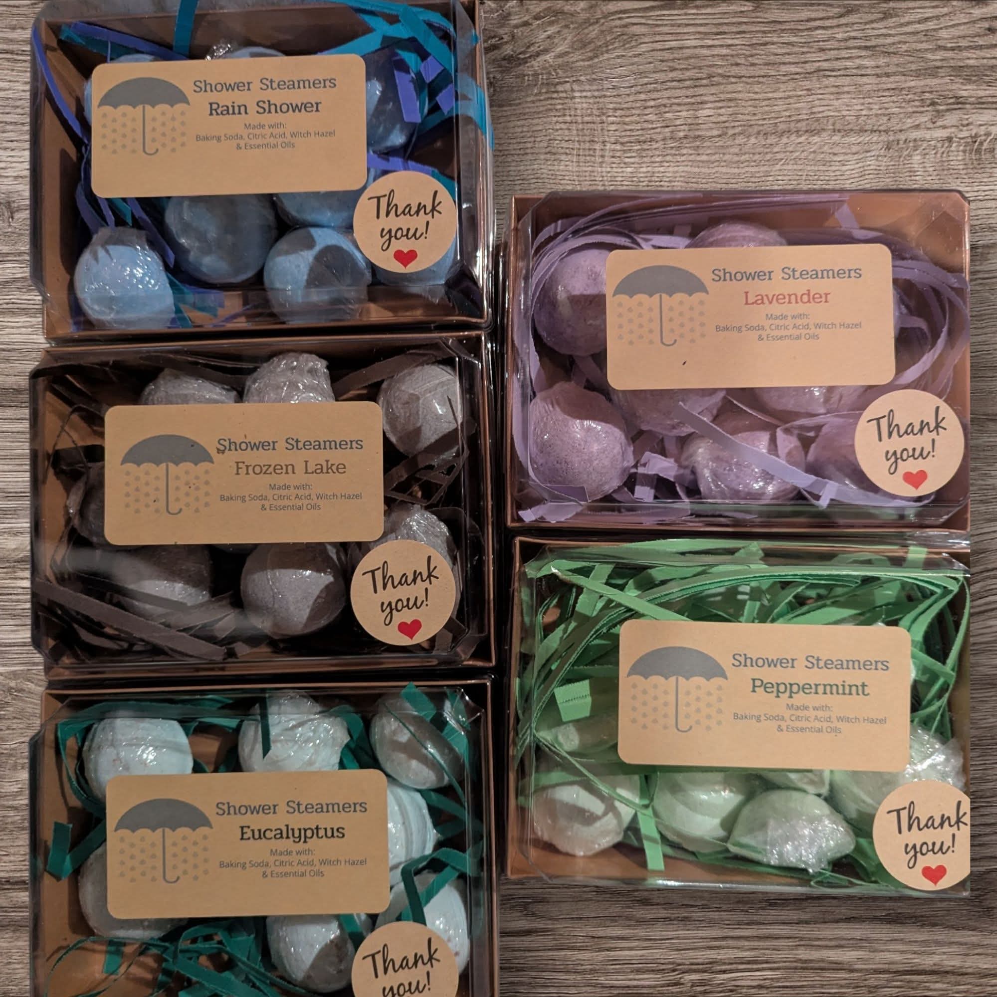 Four boxes of shower steamers with labels and 'Thank you!' tags on a wooden surface.