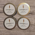 Four tins labeled 'Citronella' made with beeswax and soy on a wooden surface.