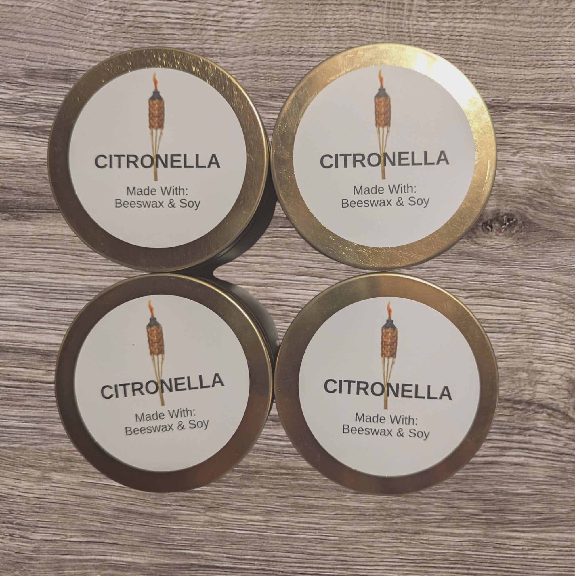 Four tins labeled 'Citronella' made with beeswax and soy on a wooden surface.