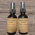 Two bottles of magnesium spray, one lavender and one cedarwood, on a wooden surface.
