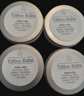 Four tins of Tattoo Balm on a black background