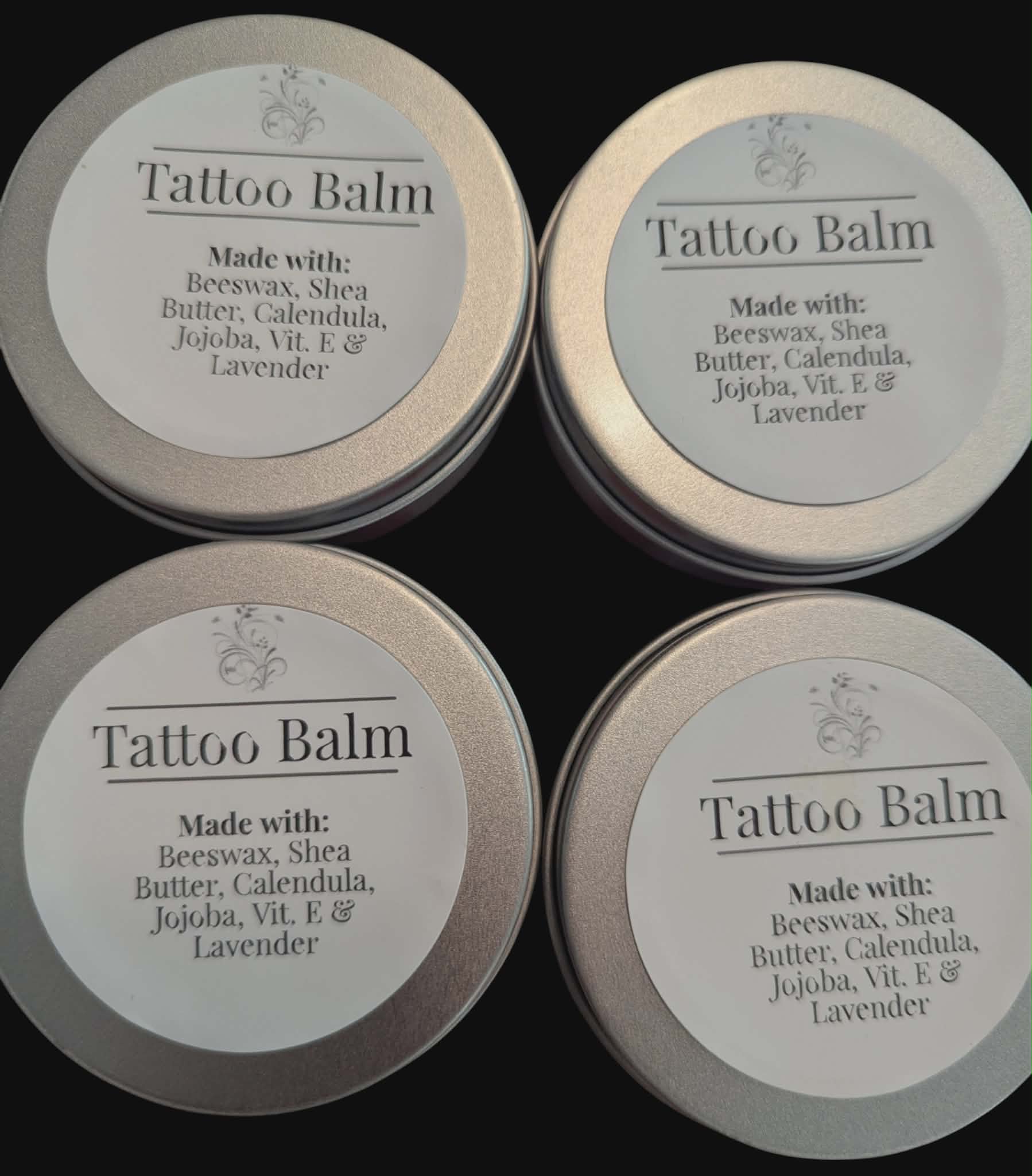 Four tins of Tattoo Balm on a black background