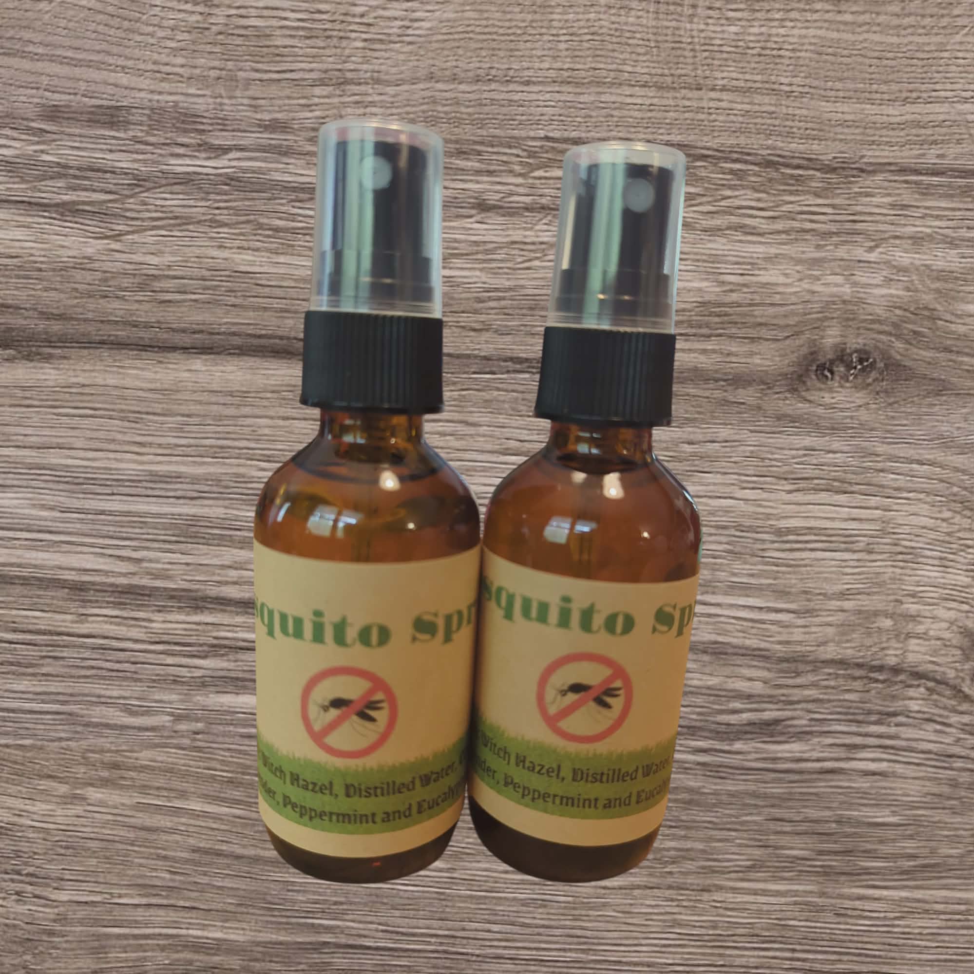 Two bottles of mosquito spray on a wooden surface