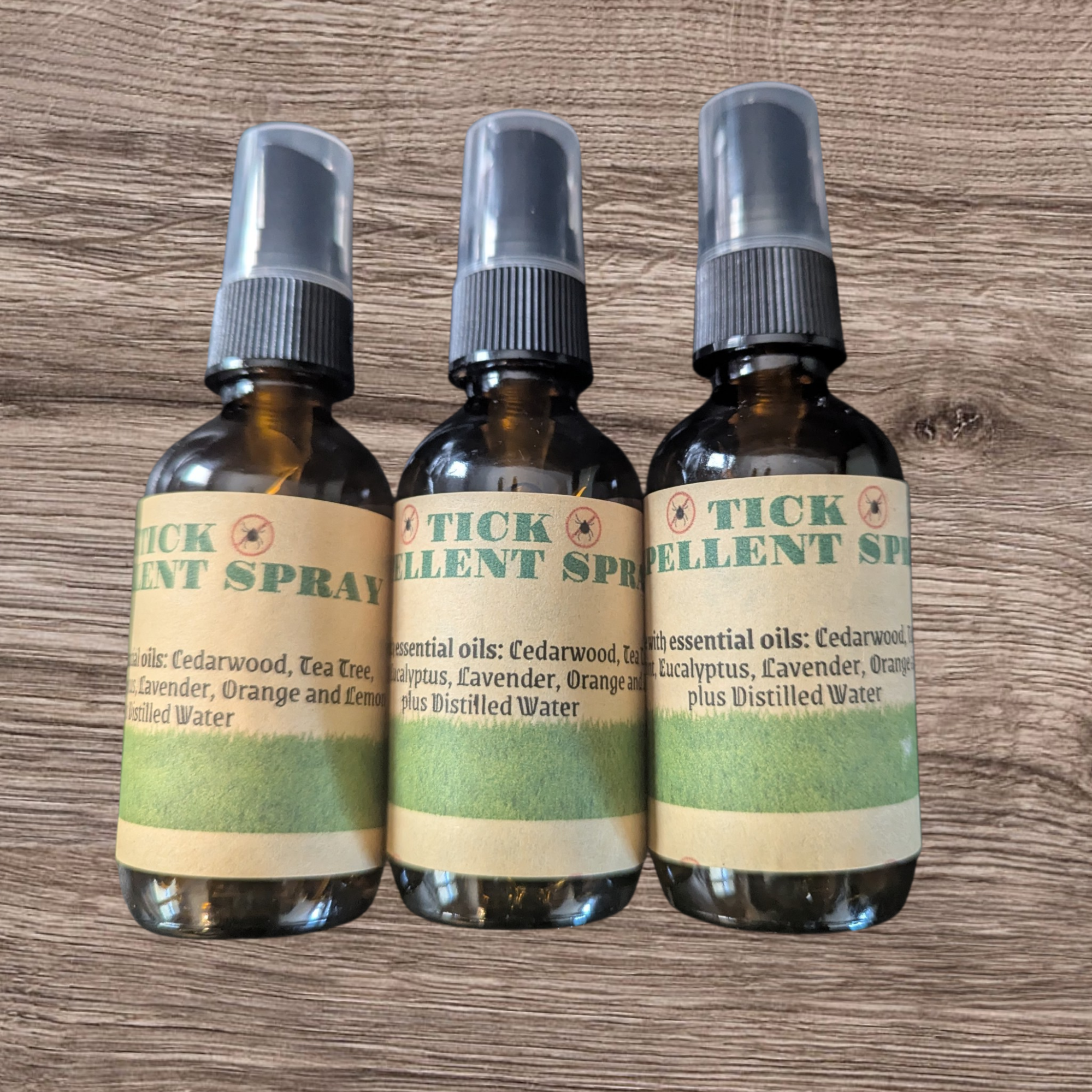 Three bottles of Tick Spellent Spray on a wooden surface